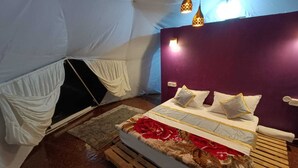 Een gezellige tentkamer met een bed, een houten bankje en een kleine tafel.