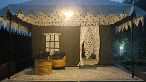 Een tent met een patroonbedekt dak, een raam en twee stoelen.