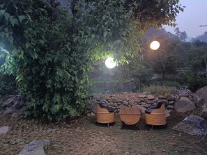 Un espacio al aire libre con muro de piedra y un árbol grande que da sombra.