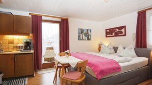 Habitació acollidora amb llit, taula de menjador i petita cuina.