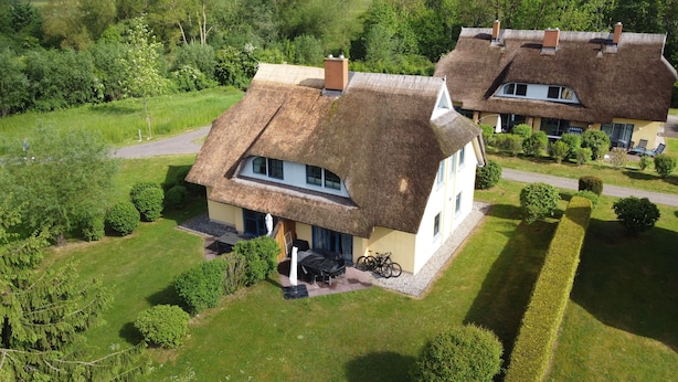 A thatched-roof house with a small patio and a bicycle. - Thatched roof house Hasel 2 (Poseritz)