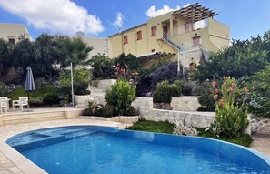 A pool area with a curved pool, stone steps, and a pergola. - 2 apartments sharing garden and pool (Vamos)