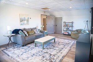 Een woonkamer met een bank, een salontafel, een boekenkast en een deur met daarop 'EXIT'.