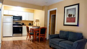 Un espacio habitable compacto con kitchenette, zona de comedor y sofá.