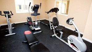 Un gimnasio con varios equipos de ejercicio, incluyendo cintas de correr, una elíptica y una banca.