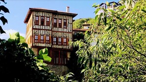 Ein traditionelles Fachwerkhäuschen mit Balkon, umgeben von üppigem Grün.