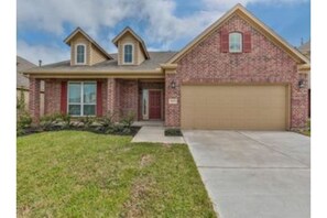 Stunning home with a central entrance, flanked by two upper-level windows, set amidst a beautifully manicured lawn.