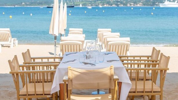 A table set for dining with a view of the sea and mountains in the background. - Lovely studio in private residence + parking. Beach, port and shops on foot (Cavalaire-sur-Mer)