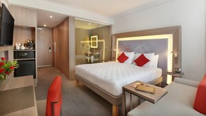 Una habitación de hotel moderna con una cama grande, un escritorio, una silla y una mesita.
