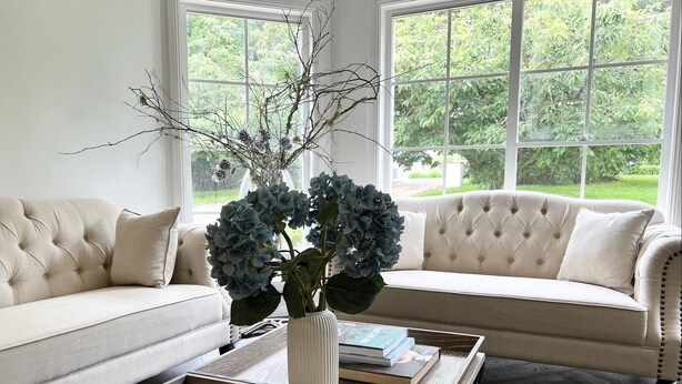 A living room with a beige sofa, a coffee table with books, and a vase with branches and blue flowers. - Grounds of Robertson. Stylish and Exclusive. (Robertson)