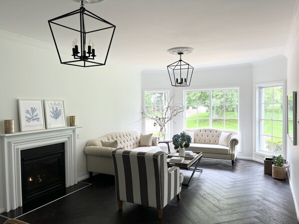 A living room with a fireplace, two sofas, a striped armchair, and a coffee table.