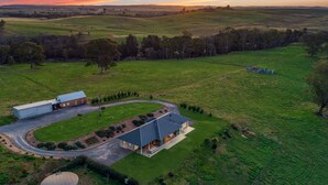 A large, modern farmhouse with a spacious layout, including a large garage and a well-maintained lawn. - The Junction Canyonleigh. Idyllic Weekends (Brayton)