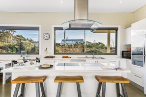 Una cucina moderna con una grande isola, sgabelli da bar, una finestra vista e un orologio appeso al muro.