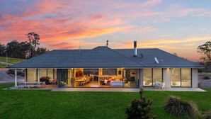 A modern house with a glass facade, an open-plan interior, and a well-maintained lawn. - The Junction Canyonleigh. Idyllic Weekends (Brayton)