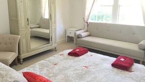 Ein Schlafzimmer mit einem großen Spiegel, einer Couch, einem Sessel und einem kleinen Nachttisch.