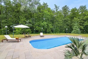 A swimming pool with lounge chairs and umbrellas, surrounded by a wooded area. - Villa Bella Elena Private Swimming Pool (Vergiate)