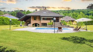 A two-story house with a swimming pool, a patio with lounge chairs, and a well-maintained lawn. - Villa Bella Elena Private Swimming Pool (Vergiate)