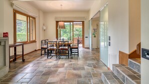 A spacious dining area with a table and chairs, a fireplace, and a view of the outdoors. - Villa Bella Elena Private Swimming Pool (Vergiate)