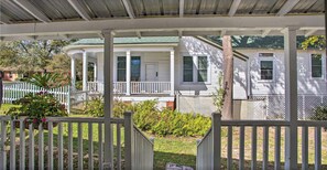 Traditional home with a covered porch, surrounded by lush greenery and a white picket fence.