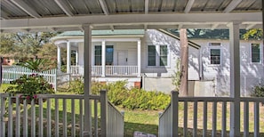 Traditional home with a covered porch, surrounded by lush greenery and a white picket fence.