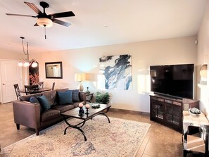 Relax in this stylish living room with a comfortable sofa, dining table, and large flat-screen TV.