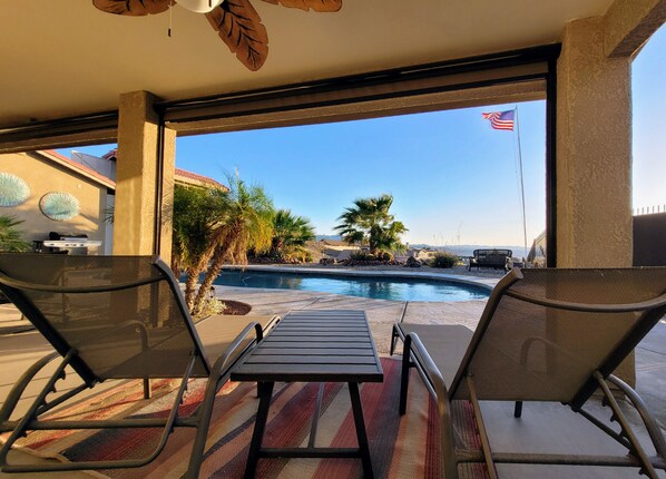 Relax by the pool with a clear view of the surrounding landscape, featuring a lounge area with two chairs and a table.