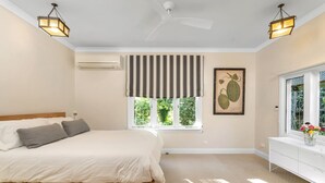 Una camera da letto con un letto, una finestra vista verde, una ventola a soffitto e un condizionatore d'aria a parete.