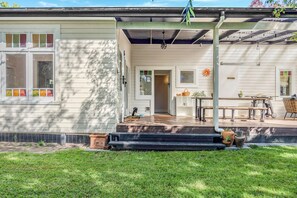 Ein Haus mit überdachter Veranda, einer Haustür und einem kleinen Garten mit Stufen, die zum Eingang führen.