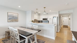 A modern kitchen with white cabinets, a central island, and pendant lighting. - Riverfront condo, Screen porch - Short walk across bridge to beach, shops, and restaurants! (Folly Beach)
