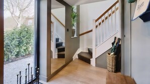 A modern interior with a wooden staircase, a wicker basket, and a view of the outdoors. - Little Hayloft by Bloom stays -  charming barn with hot tub (Canterbury)