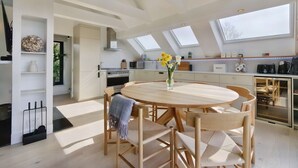 A modern kitchen with skylights, a round wooden dining table, and a vase with flowers. - Little Hayloft by Bloom stays -  charming barn with hot tub (Canterbury)