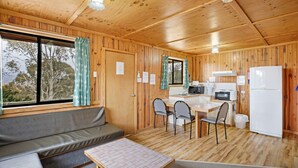 A wooden cabin with a dining area, kitchen, and seating area. - Providence Park (Providence Portal)