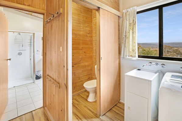 A wooden interior with a shower, toilet, and sink, and a window with a view. - Providence Park (Providence Portal)