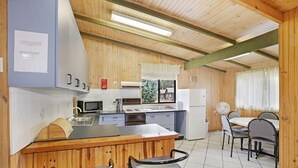 A kitchen with wooden walls, a bar area with stools, and a dining table with chairs. - Providence Park (Providence Portal)