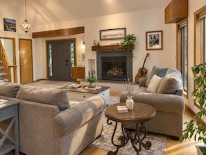A living room with a fireplace, sofas, a coffee table, and a guitar. - Lake View Berkshire Retreat – Private Setting Near Lenox (Lee)