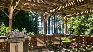 An outdoor patio with a grill, chairs, and a view of a lake. - Lake View Berkshires Retreat - Private & Minutes to Lenox (Lee)