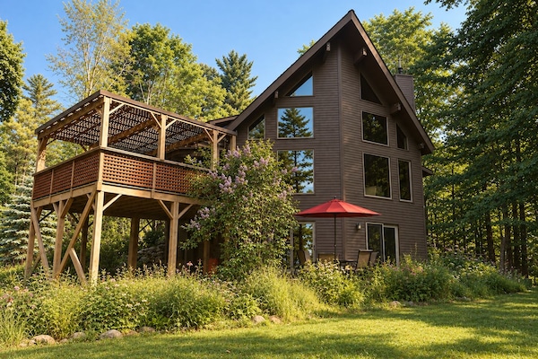 Back of house with expansive windows, a covered deck, patio and beautiful views.