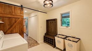 A laundry room with a washer, dryer, and two bags labeled 'Deluxe Laundry Service.'