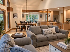 A modern living room with a sofa, a coffee table, and a dining area with chairs and a table. - Lake View Berkshire Retreat – Private Setting Near Lenox (Lee)