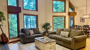 A spacious living room with large windows, a fireplace, and a dining area. - Lake View Berkshires Retreat - Private & Minutes to Lenox (Lee)
