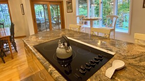 A kitchen with a black stovetop, white chairs, and large windows offering a view of greenery. - Lake View Berkshires Retreat - Private & Minutes to Lenox (Lee)