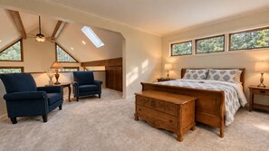 Quarto com cama, duas poltronas, um banco de madeira e um ventilador de teto.