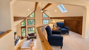 Un loft spacieux avec de hauts plafonds, de grandes fenêtres et un coin salon confortable avec un canapé et des fauteuils.