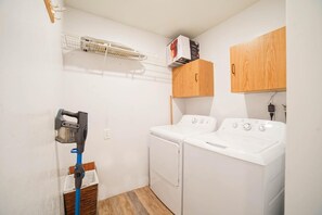 A laundry room with two white washing machines, a drying rack, and a blue mop. - Beautiful Stylish Home With Hot Tub (Puyallup)