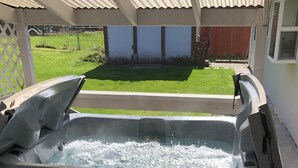 A hot tub on a wooden deck with a wooden stump nearby. - Beautiful Stylish Home With Hot Tub (Puyallup)