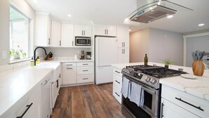A modern kitchen with white cabinets, a stainless steel stove, and a microwave. - Beautiful Stylish Home With Hot Tub (Puyallup)