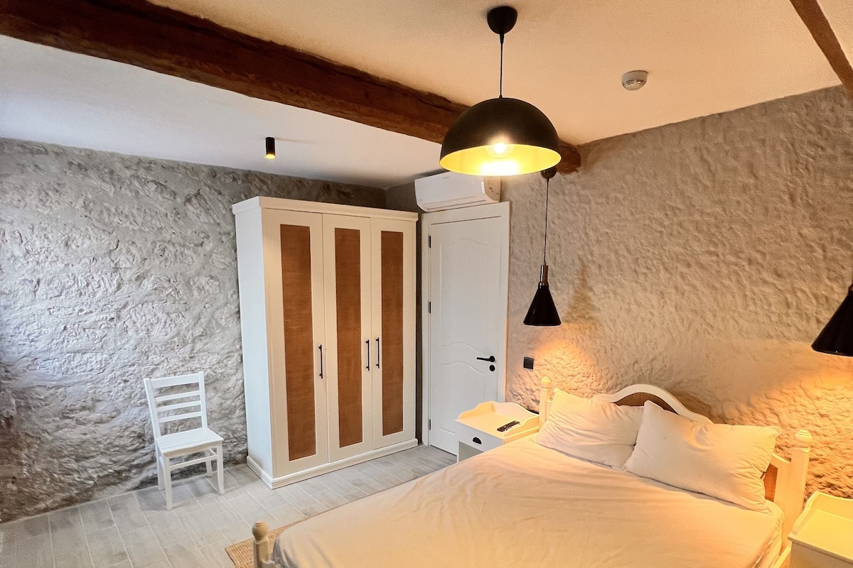 A bedroom with a bed, a wardrobe, a chair, and a nightstand.