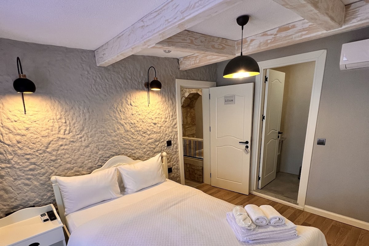 A bedroom with a large bed, bedside tables, a wardrobe, and a mirror.