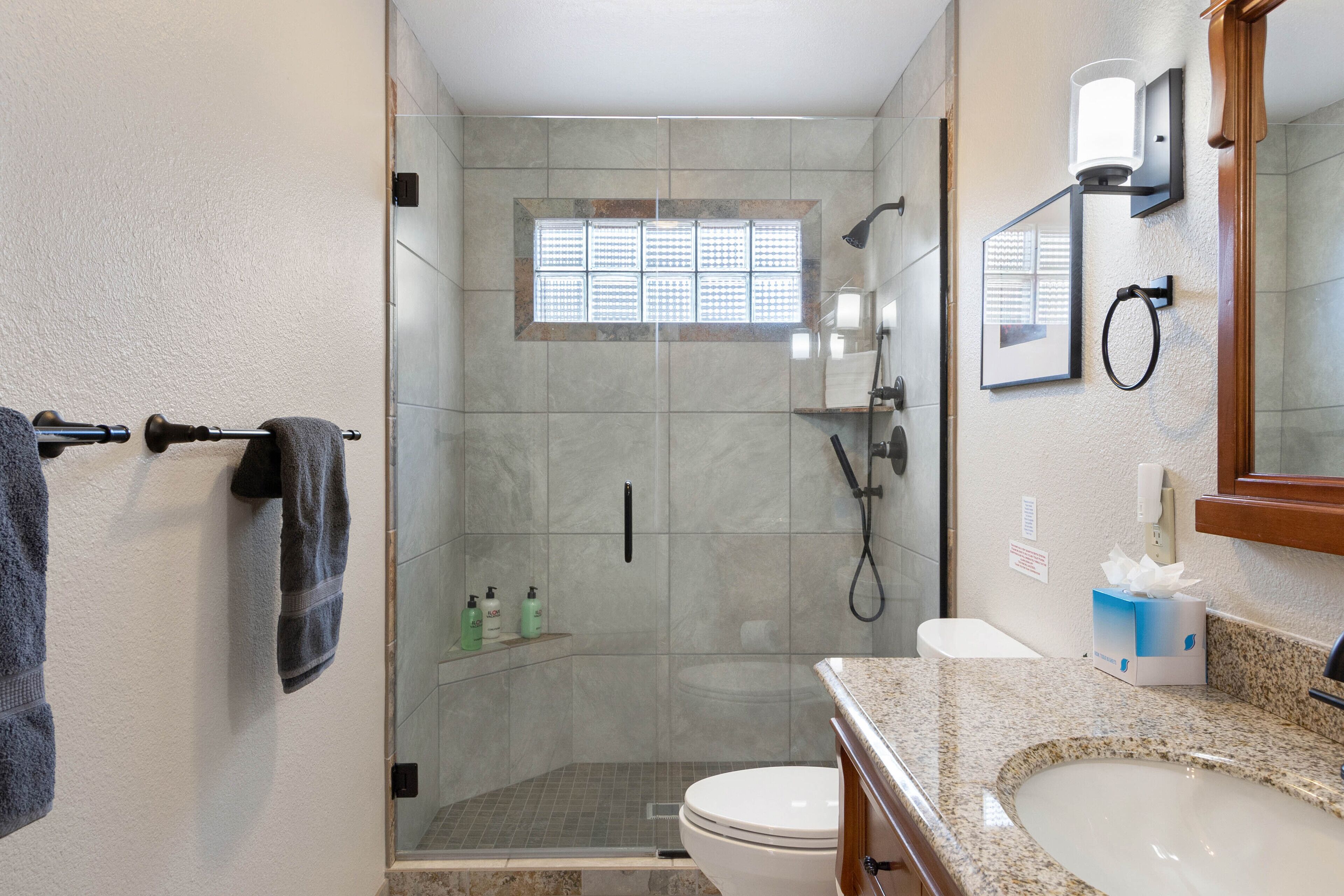 A bathroom with a glass-enclosed shower, a toilet, a sink, and a towel rack.