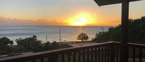A balcony with a view of the sunset over the ocean.